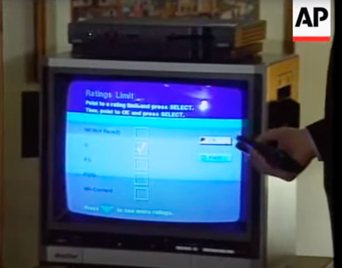 Écran télévisé montrant une démo du V‑chip en 1996, avec les options de contrôle parental et une télécommande sélectionnant des restrictions.